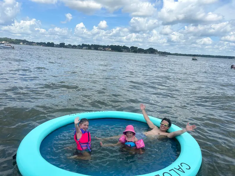 Dad and two kids playing in a floating island next to the Veranda V22RC on Lake Conroe